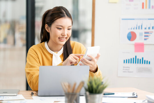Smiling Young Woman Working on Laptop in Creative Office