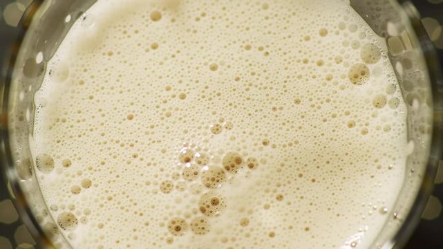 Close-up of foamy beer in a glass, refreshing beverage, macro bubbles