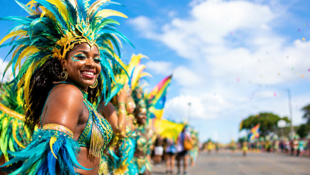 Beautiful smiling West Indian Day Parade in vibrant feather costume celebrating at a sunny outdoor carnival parade, close up portrait