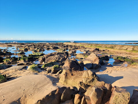 A rock pool at low tide on the rock platform at Susan Gilmore Beach Newcastle New South Wales Australia. Surrounded by broken rocks and boulders