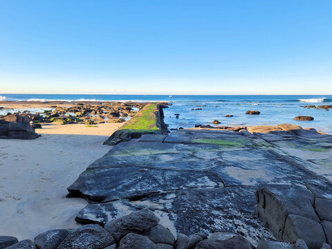 Concrete sea wall at Susan Gilmore Beach Newcastle New South Wales Australia. Taken at low tide with green algae exposed