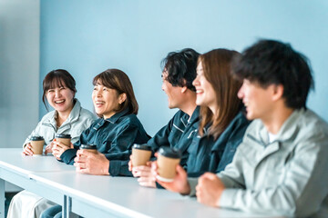 Fototapeta premium A woman and a man in work clothes drinking coffee in the office break room.