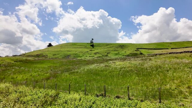 Idyllic green rolling hills of the English countryside under a beautiful blue sky with white clouds. slow motion