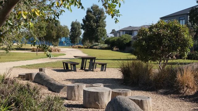 A picnic table sit within a landscaped park featuring green space, gum trees and native grasses in Point Cook, Melbourne Australia. desirable community park amenities in a new estate.