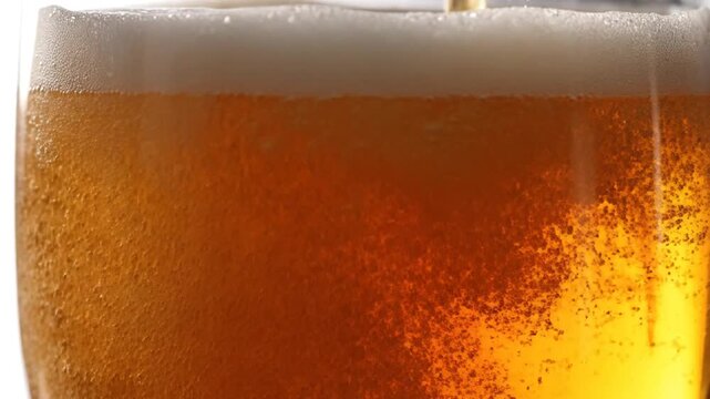 Close-up of golden beer being poured into a glass with frothy foam and bubbles