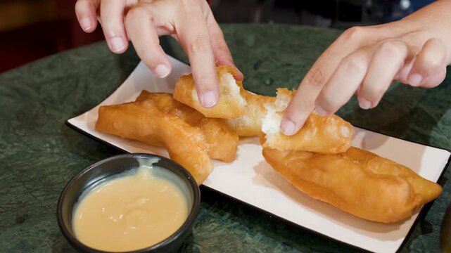 Person Dipping Fried Dough Youtiao into Sweet Condensed Milk