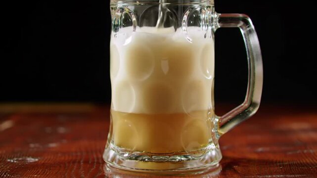 Golden beer pouring into a textured glass mug, close-up, refreshing beverage.