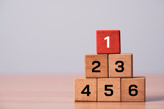 Wooden blocks arranged as a ranking podium with the number one highlighted for business ranking and first place represent leadership achievement successful on top performance and winning strategy.