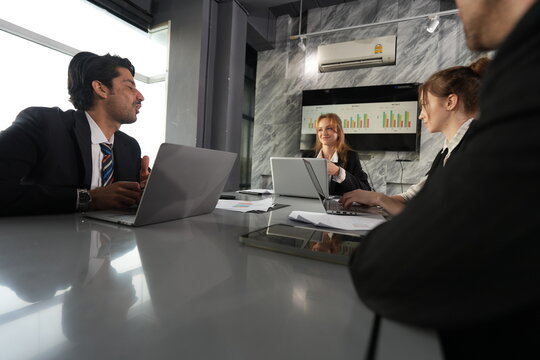 Analyst reaches toward the keyboard mid task as the manager watches thoughtfully, sunlight flooding the boardroom through floor length glass in a bright modern coworking office.