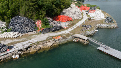 Aerial view of large stacks of colorful fishing buoys stored near a pier and coastal marine infrastructure © soya
