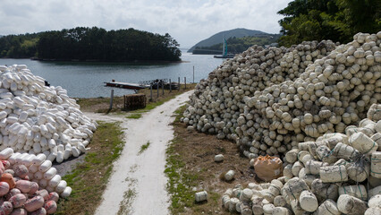 Storage yard with white fishing buoys and floats beside the sea. Equipment used for aquaculture commercial fishing and marine farming. © soya