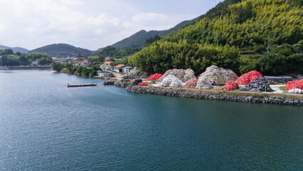 Aerial view of a coastal storage yard with fishing buoys and aquaculture equipment located beside the sea. © soya