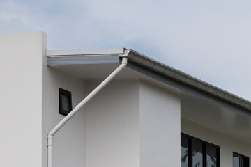 Modern home features sleek white gutters against plain white walls © Rattanachat