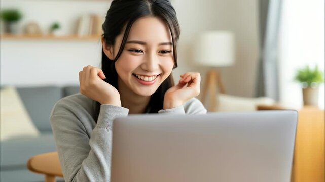 自宅でノートパソコンの画面を見て嬉しそうに微笑む女性