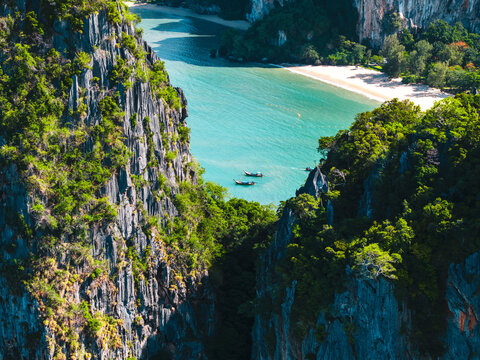 Traditional Thai longtail boats floating in turquoise sea between cliffs