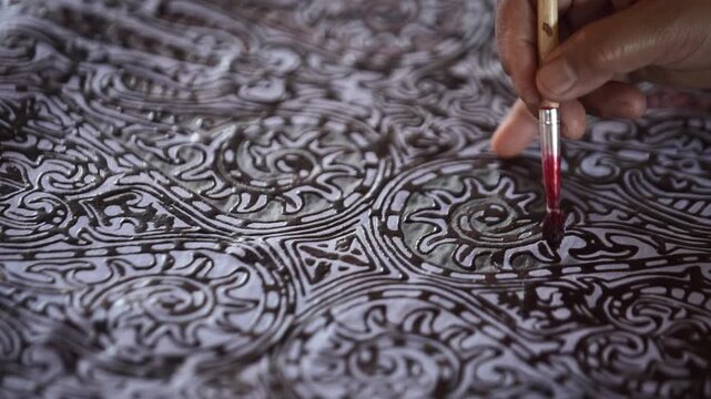 Hand painting intricate traditional decorative pattern with fine brush.