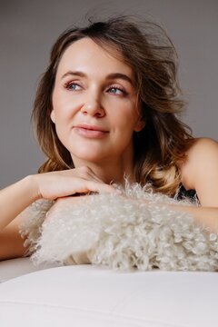 Female portrait. Pensive face. Carefree dreamy woman on white sofa relaxing on soft comfortable cushion enjoying cozy atmosphere.