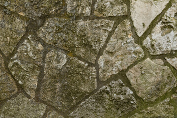 Fototapeta premium Old Weathered Stone Wall Texture Background Rustic Aged Surface with Mossy Patches for Architecture and Construction Concepts