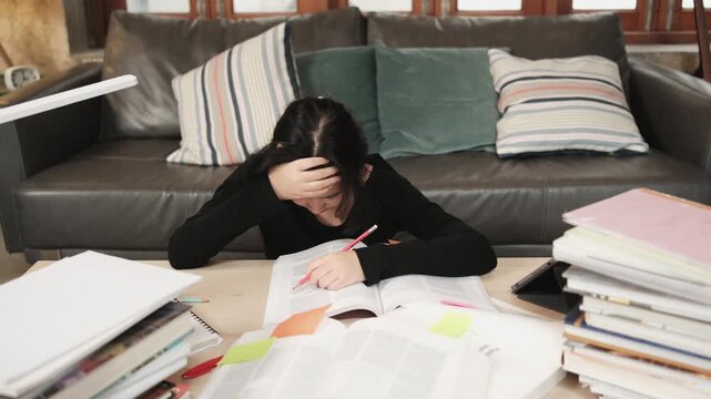 College Asian teenage girl tired and burned out from overwhelmed study pile of books, stressed learning at home with stack of textbooks, reading and writing for school exam, homeschooling education.