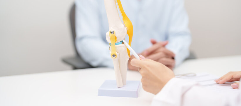 Doctor with Human Knee joint anatomy model. Osteoarthritis, Patellofemoral Pain Syndrome, Patellar Tendinitis, ACL, Anterior Cruciate Ligament, PCL, Posterior, MCL, Medial Collateral, LCL and Lateral