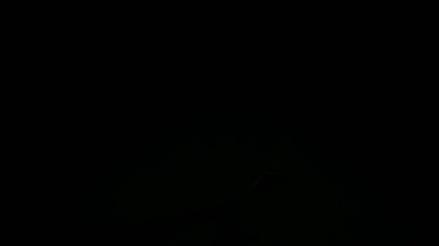 Airplane wing is illuminated by a red navigation light at night.