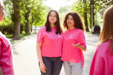 Fototapeta premium Group of diverse smiling women wearing pink t shirts supporting breast cancer awareness on street