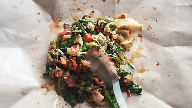 A traditional Indonesian dish called Lotek, consisting of a mixture of vegetables and peanut sauce being tossed together.