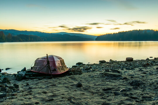 Overturned boat on the shore of Lipno Reservoir at sunset in Frymburk