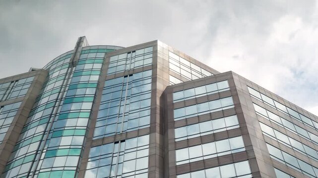 Time-lapse of a modern glass skyscraper corporate building under bright afternoon sky, concept of business success.