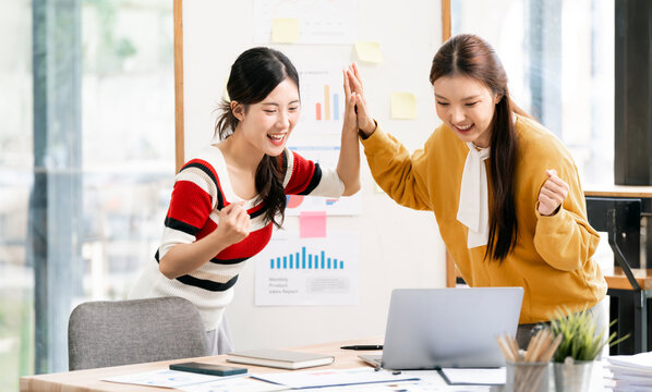 Two Happy Asian Businesswomen Giving High Five to Celebrate Success in Office