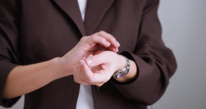 Business style. Morning routine. Unrecognizable woman hands in brown blazer adjusting silver wristwatch preparing for workday.
