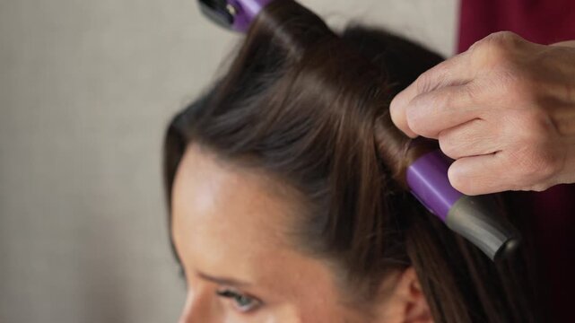 Hair styling curling iron salon professional creating beautiful curls for elegant woman