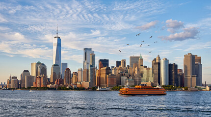 Obraz premium New York City skyline with One World Trade Center and Staten Island Ferry at sunset, Lower Manhattan cityscape, USA.