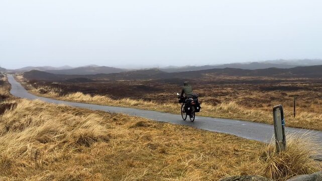 Lone cyclist riding a touring bike on a rural path