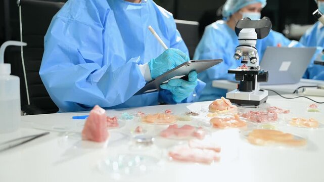 Biomedical scientists perform laboratory research using microscopes and pipettes. Medical testing, biotechnology, healthcare innovation in modern lab.