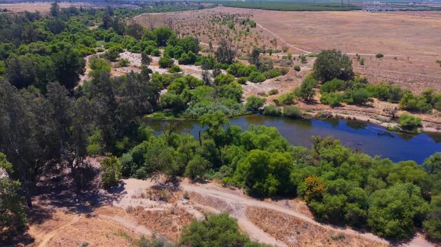 Arc Shot Aerial Drone Left to Right Over San Joaquin River With Trees Bushes and Hiking Trails in Fresno California