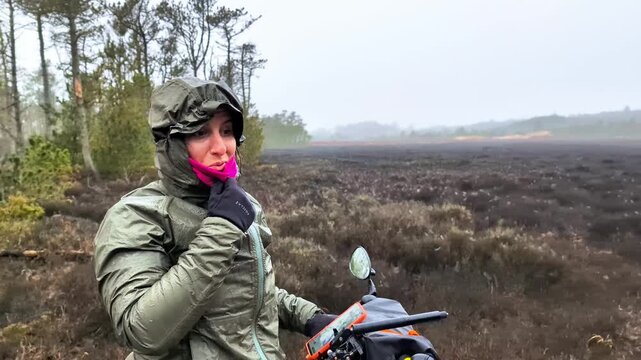 Woman riding her bicycle in the rain in a Danish forest