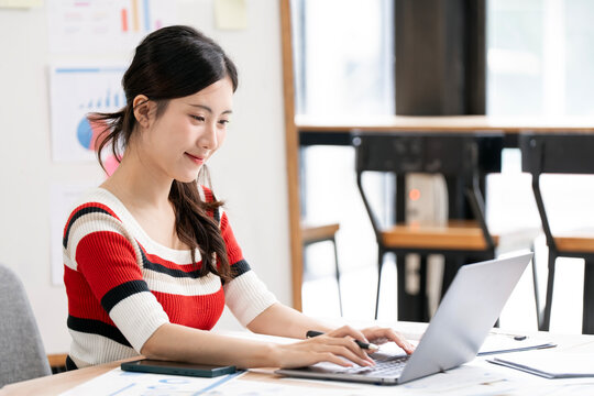 Side View of Young Asian Businesswoman Working on Laptop with Copy Space