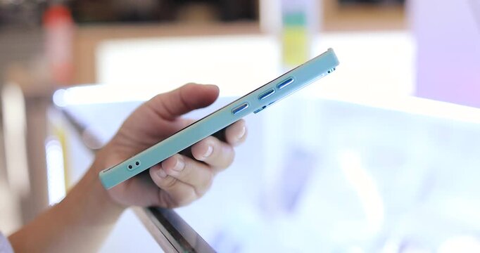 Hands using and holding a smartphone in an mobile phone store, Technology, mobile device, electronics store, retail shopping, consumer electronics, and digital lifestyle concept, close-up