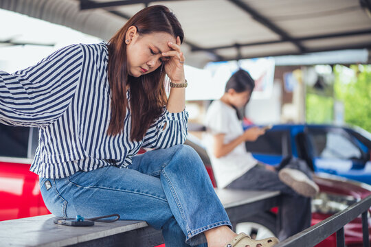 Depressed and stressed Asian middle-aged woman sitting lonely on a bench with head in hands inside an industrial background. Concept of financial crisis, business bankruptcy, debt pressure, mental hea