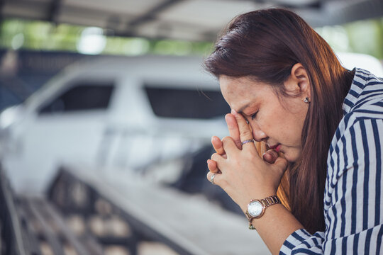 Depressed and stressed Asian middle-aged woman sitting lonely on a bench with head in hands inside an industrial background. Concept of financial crisis, business bankruptcy, debt pressure, mental hea