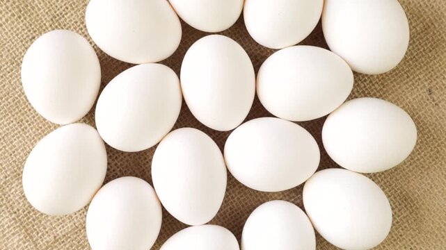 White chicken eggs rotating slowly on a rustic burlap background