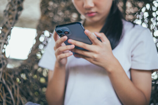 Worried and stressed Asian teenager girl holding smartphone looking at screen with anxious expression. Concept of cyberbullying, social media peer pressure, smartphone digital addiction, and youth men