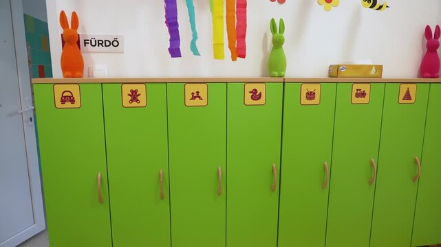 Bright green lockers with toy pictograms inside a brightly decorated kindergarten changing room