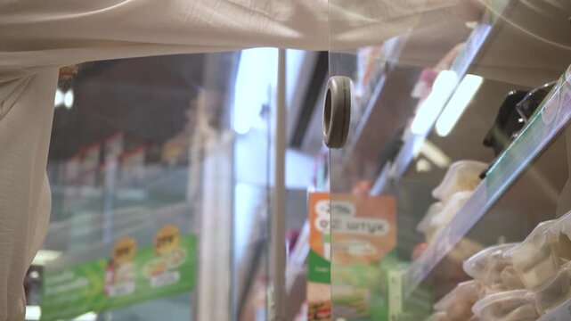 A Person Interacting with a Display Case in a Store: Capturing the Moment of Hand Reaching to Open Up a Glass Door for Product Selection