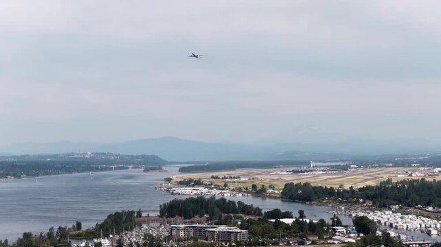Wide aerial of Portland Oregon airport with plane taking off with view of Mount Hood with hazy skies in summer