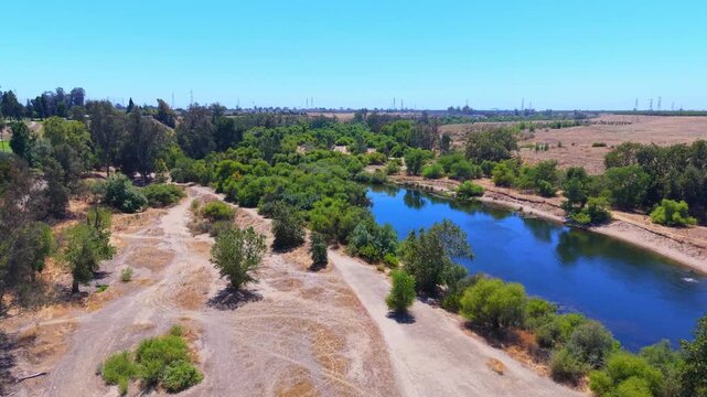 Forward Moving Aerial Drone Shot Over San Joaquin River With Trees Bushes and Power Lines in Fresno California