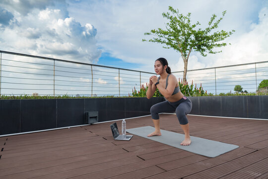 Woman exercising squat on rooftop with online fitness coaching