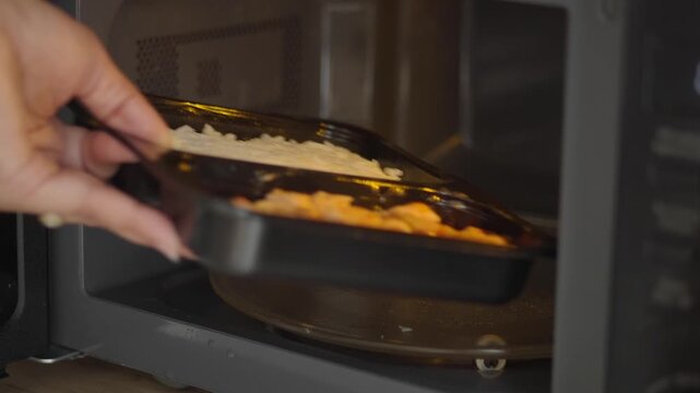 Person Placing Prepackaged Meal Into Microwave