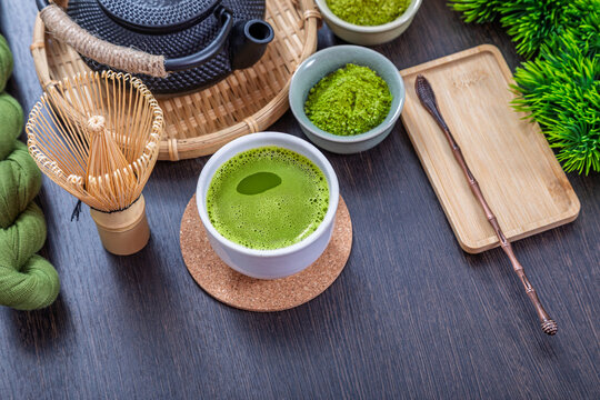Matcha tea in bowl with bamboo whisk and powder. Traditional japanese ceremony beverage set on wooden table. Healthy organic green drink for wellness relaxation and morning refreshment